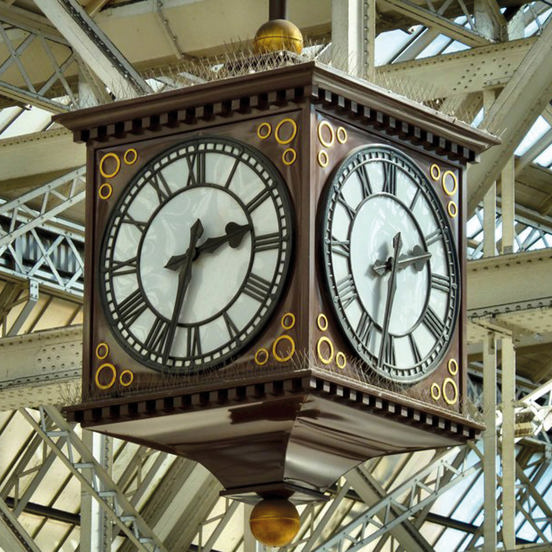large brown cubic ornate clock hanging from the ceiling, with 2 clock faces showing