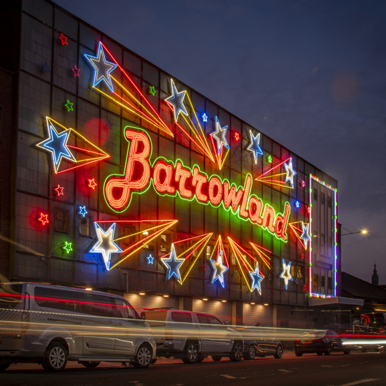 Large building covered with a bright orange neon sign saying Barrowlands and colourful neon stars