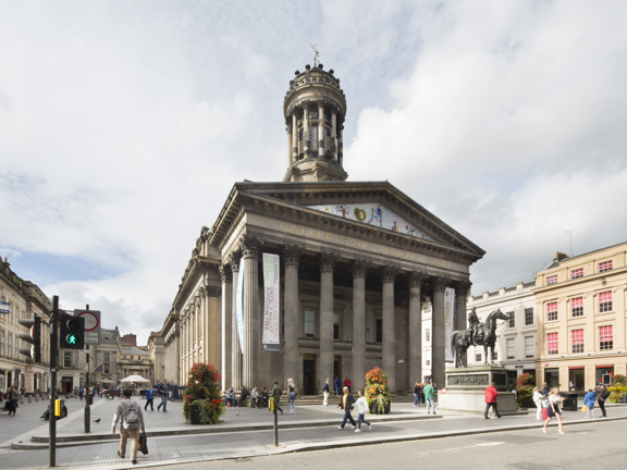 An exterior view of the Gallery of Modern Art and its position on Royal Exchange Square. The image shows a large sandstone building dominated by eight, 2-storey Roman composite columns. The building has a peaked roof and a Niiki de Saint Phalle mosaic can be seen in the gable end. The building is surrounded by a pedestrian square with grand Victorian buildings around it. At the front of the building a sculpture of the Duke of Wellington on a horse can be seen atop a large stone plinth. 