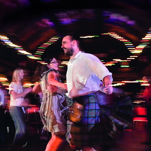 a man and woman spinning with liked arms, ceilidh dancing