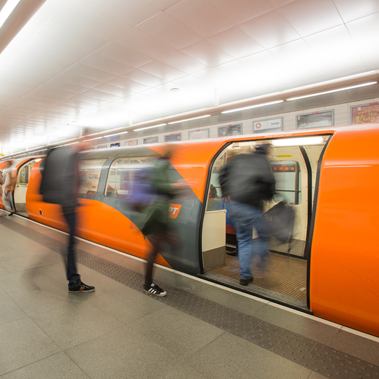 Blurred picture of people getting on to an orange subway car