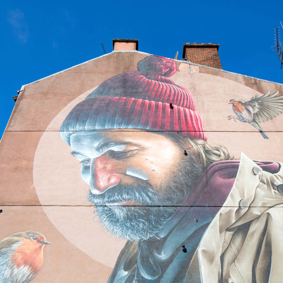 mural of a bearded man in red bobble hat looking at a red robin