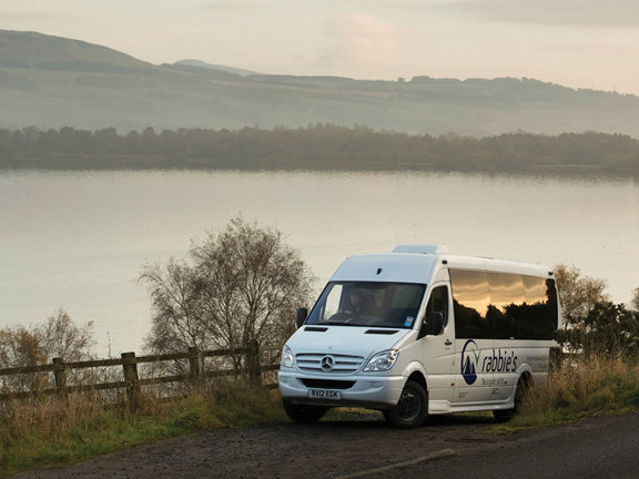 Minibus with Rabbie's tours signage beside a lake