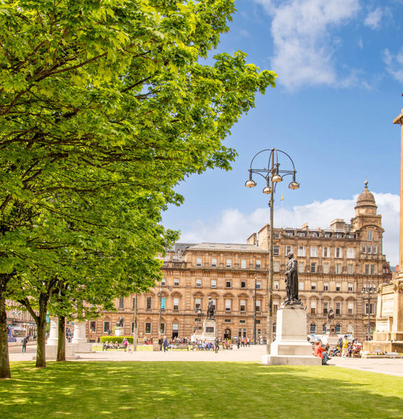 sunny view of tree-lined George Square, with a 24m column in the centre with a statue of Sir Walter Scott