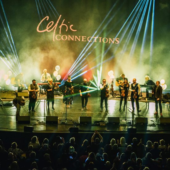 A band perform on stage, in front of a Celtic Connections sign.
